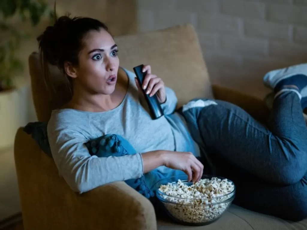 jovem mulher na poltrona assistindo filme