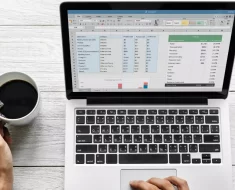 Computador com planilha de finanças na tela com café preto