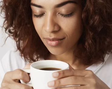 Mulher de cabelo cacheado tomando café