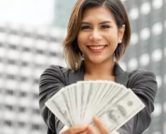 Mulher de negócios sorrindo com dinheiro na mão