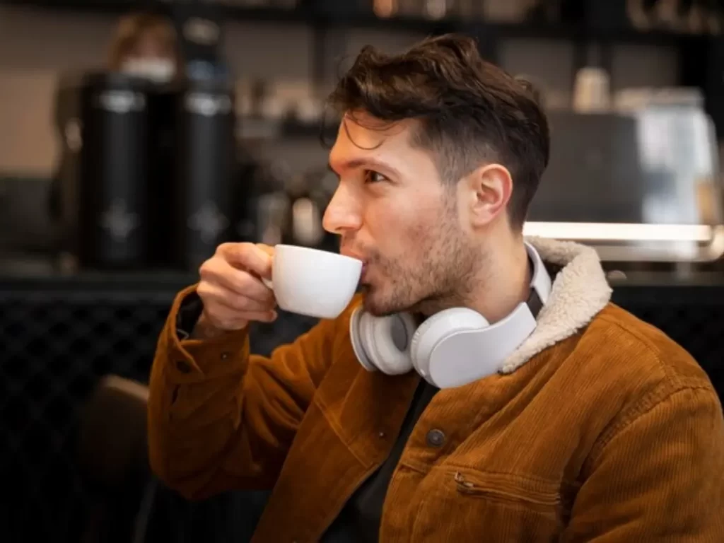 homem tomando café com fone de ouvido