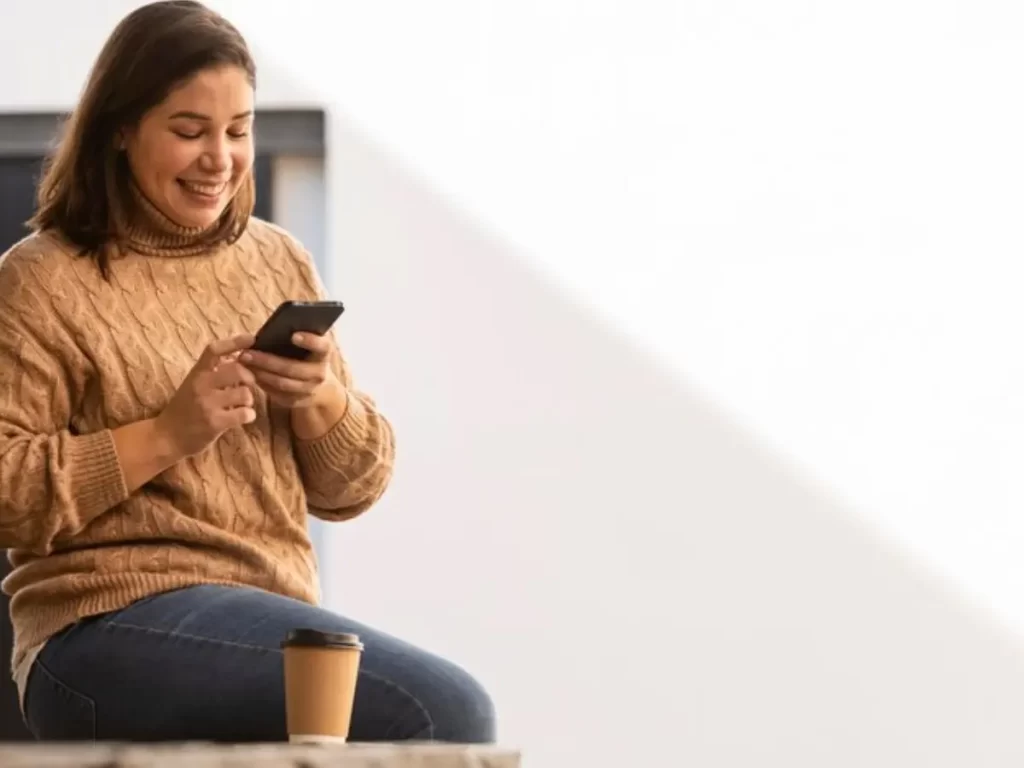 mulher sorrindo e digitando no celular