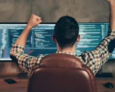 Homem na frente do monitor feliz programando