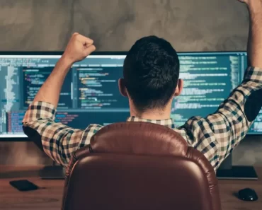 Homem na frente do monitor feliz programando