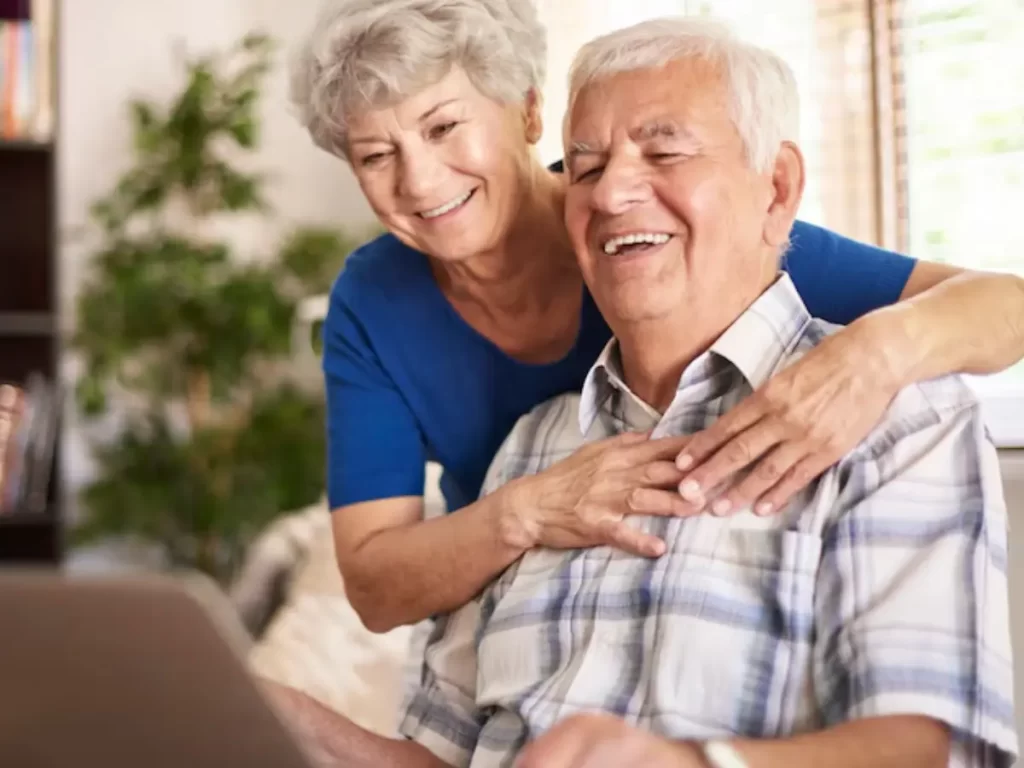 dois idosos sorrindo abraçados